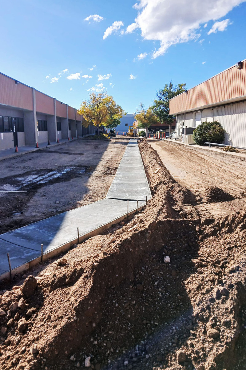 A business parking lot with concrete drainage in the center that is torn up before being repaved