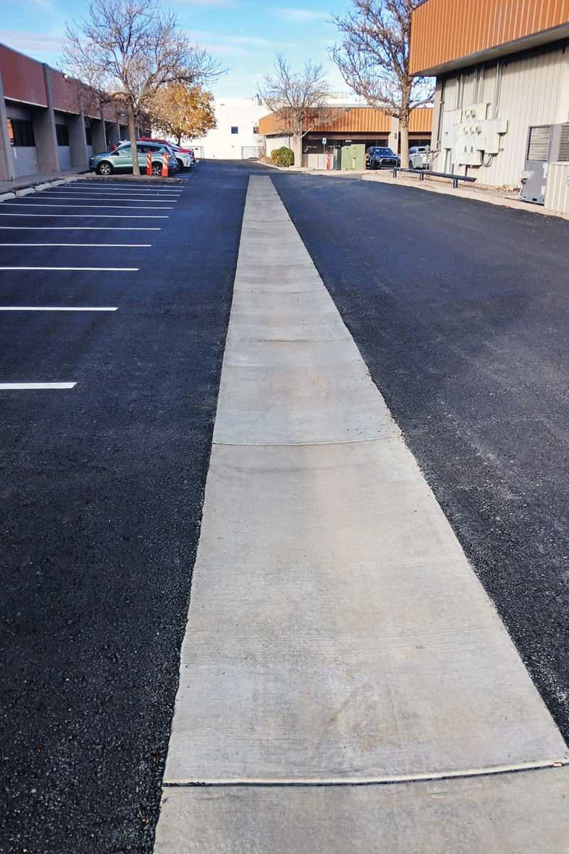 A repaved business parking lot with center concrete drainage pan